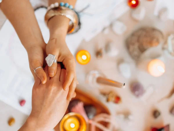 Two people holding hands beside candles