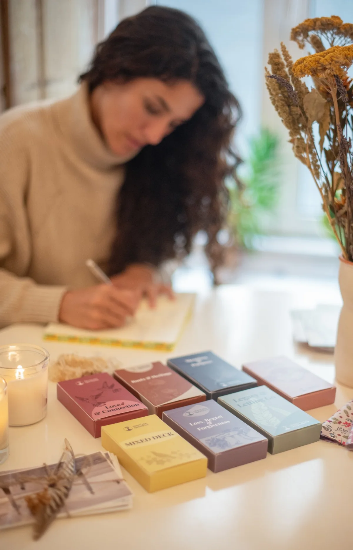 Death Bed Questions decks laid out on a table beside candles and dried flowers